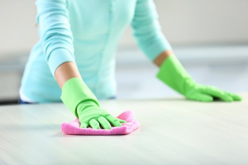 Cleaner wiping down kitchen cupboards during a move in clean